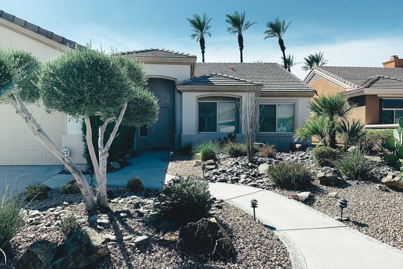 Single-story home with desert landscaping and palm trees