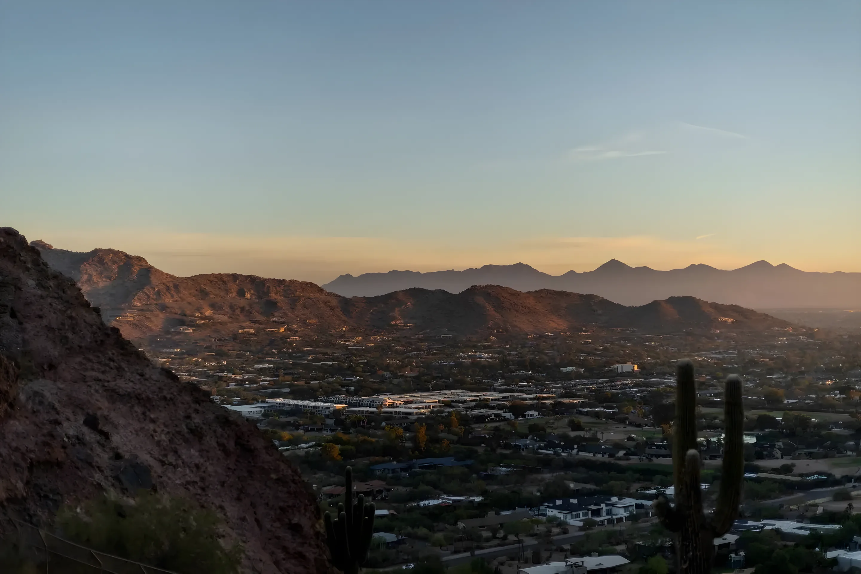 Phoenix valley at sunset seen from a desert ridge with saguaro cactus