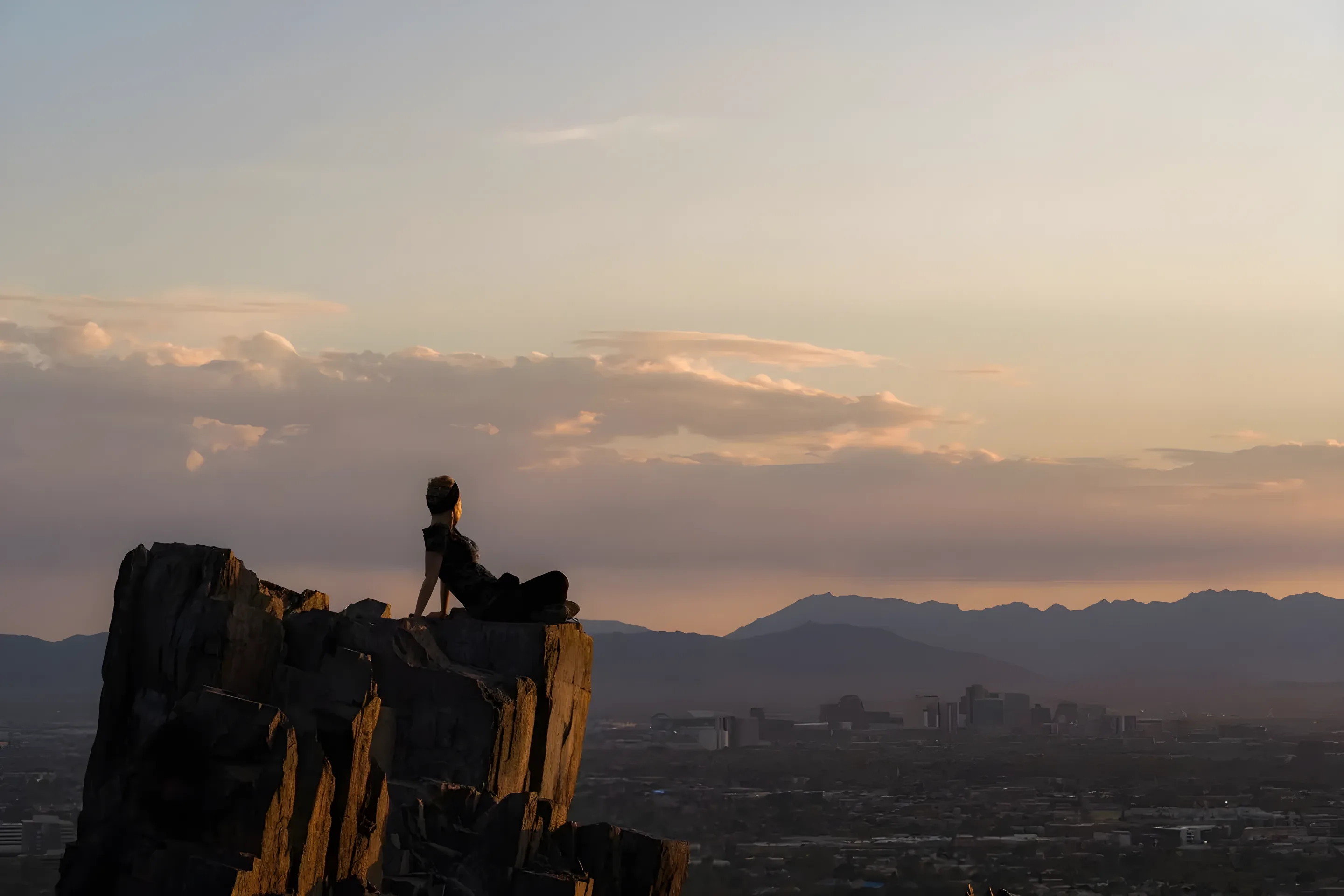 Hiker on a rocky summit overlooking Tempe at sunset